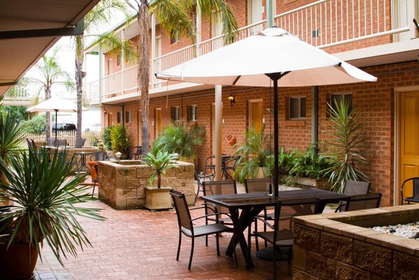 An outdoor patio with brick walls, potted plants, and outdoor seating.