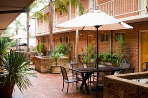 Un patio al aire libre con paredes de ladrillo, plantas en macetas y mobiliario exterior.