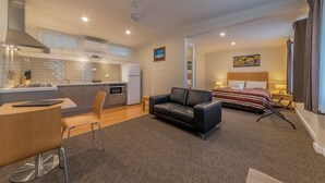 Een knus woongedeelte met een kitchenette, een slaapbank, een bed en een eethoek.