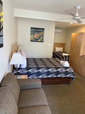 Una habitación de hotel con cama, sofá, ventilador de techo y un cuadro en la pared.