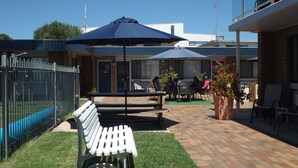 Un espace extérieur aménagé avec un banc, des sièges et des parasols.