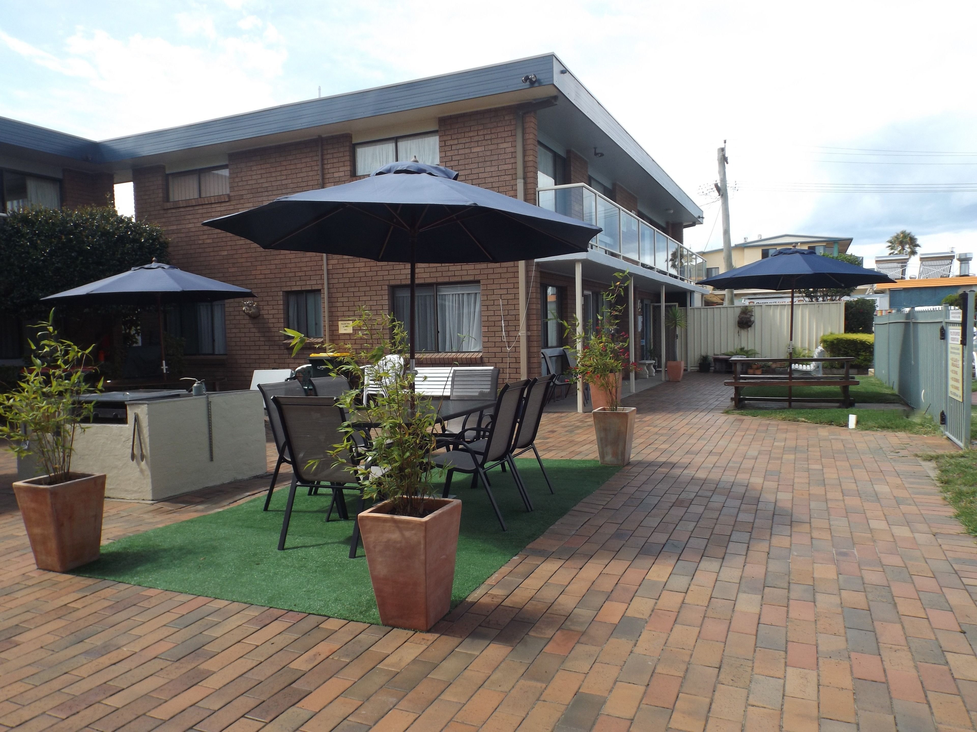 A patio area with outdoor seating, including tables and chairs, and two umbrellas providing shade.