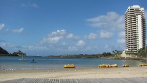 A beach with a wooden boardwalk, a tall hotel named 'Seascape', and yellow watercraft on the shore. - Tweed Central Motel (Tweed Heads)