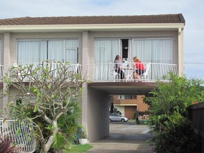 A two-story residential building with a balcony, a car parked in the driveway, and various plants around the property. - Tweed Central Motel (Tweed Heads)