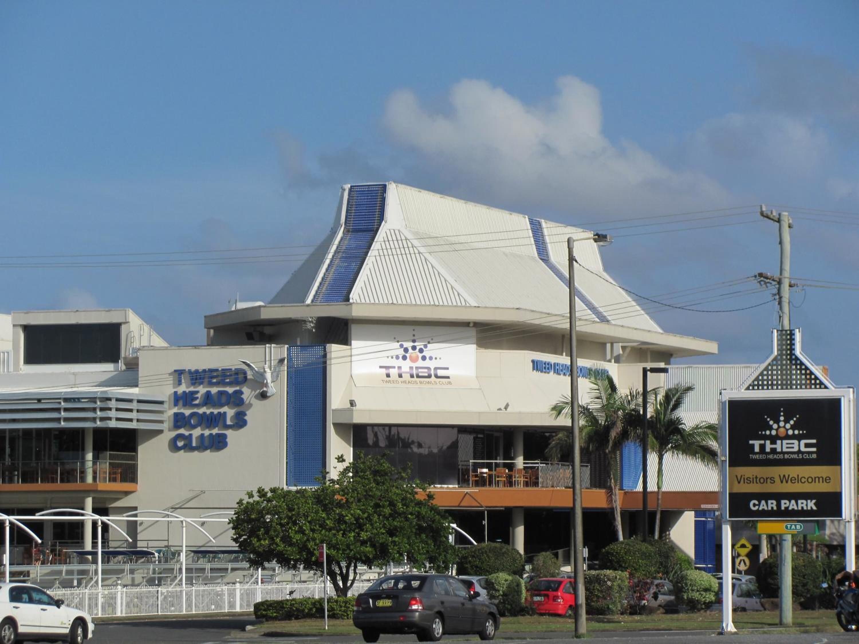 A building with a sign for Tweed Heads Bowls Club and a sign indicating a car park.