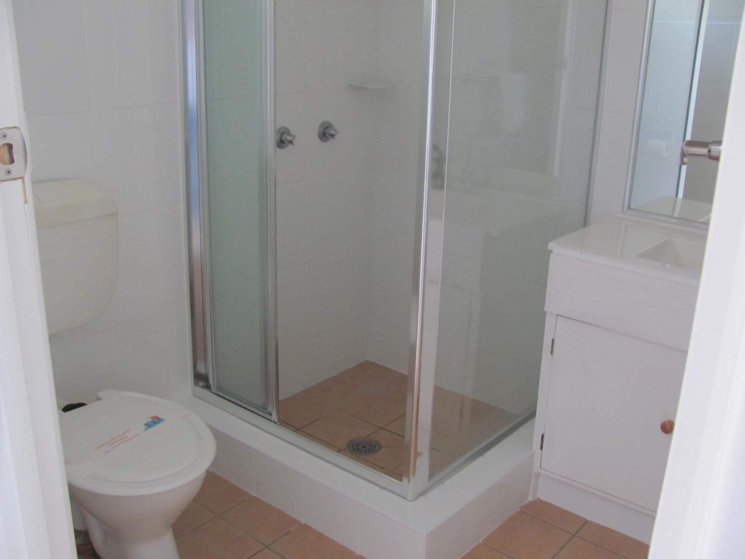 Une salle de bain avec une douche à parois de verre, des toilettes et un lavabo.