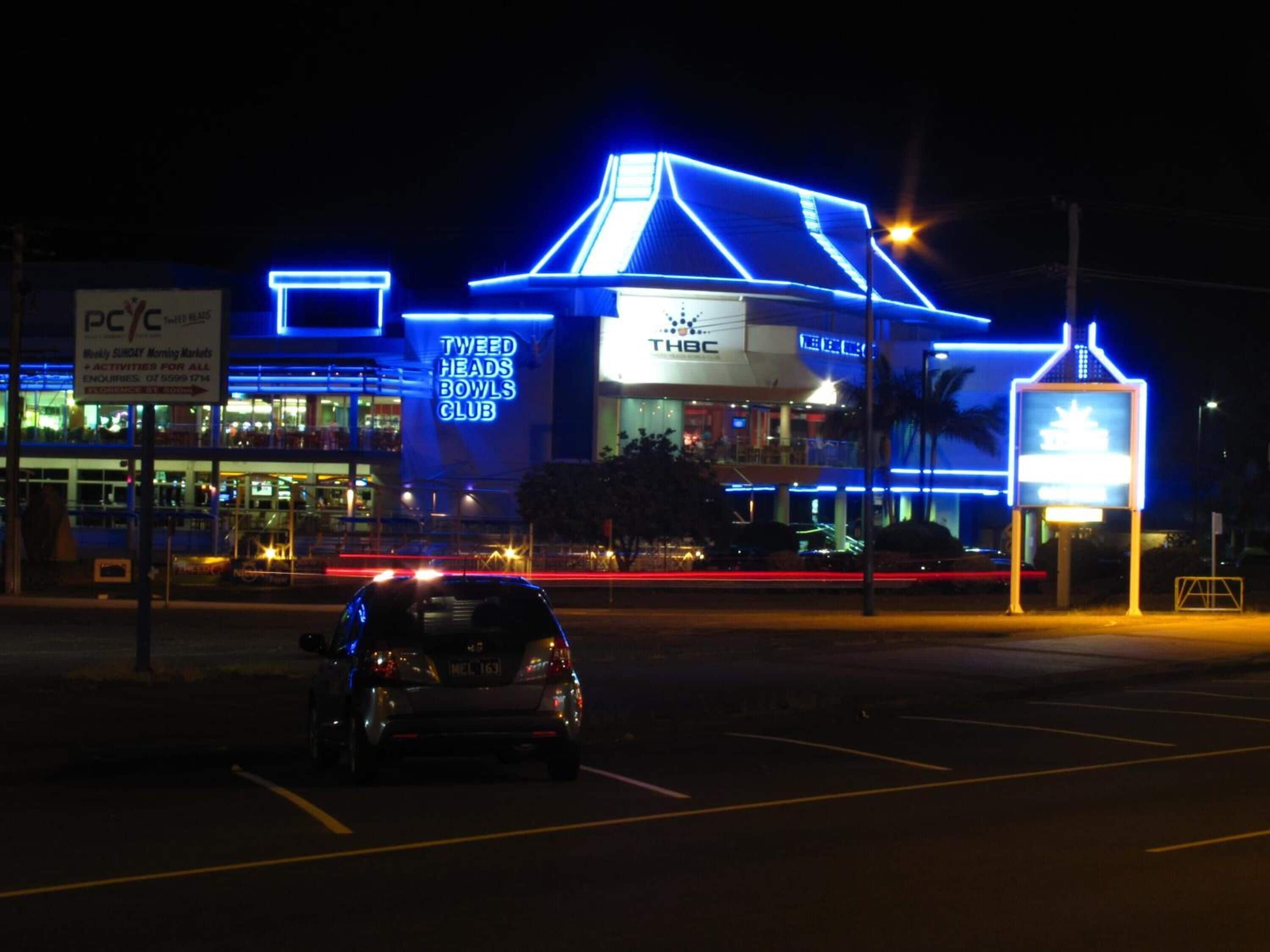 Un edificio con letreros de neón para Tweed Heads Bowls Club y THBC.
