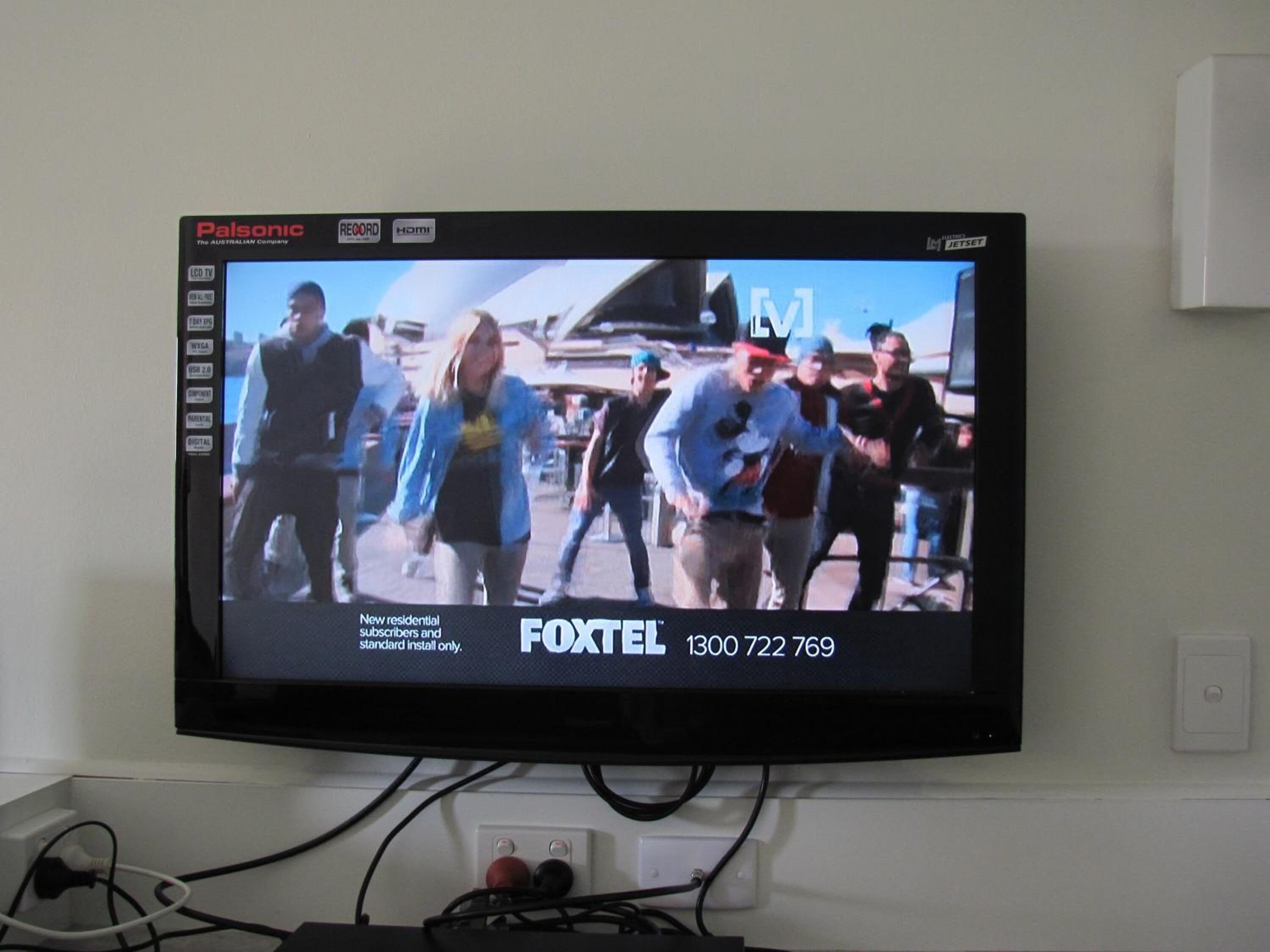 Un televisor mostrando un programa de noticias con un número de contacto visible para Foxtel.
