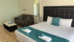 A hotel room with a large bed, a sofa, a small table, and a mirror. - Tweed Central Motel (Tweed Heads)