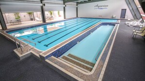 Ein Hallenbad mit deutlich abgegrenzten Bahnen, einer gefliesten Kante und einem Schild mit der Aufschrift 'Aquarius'.