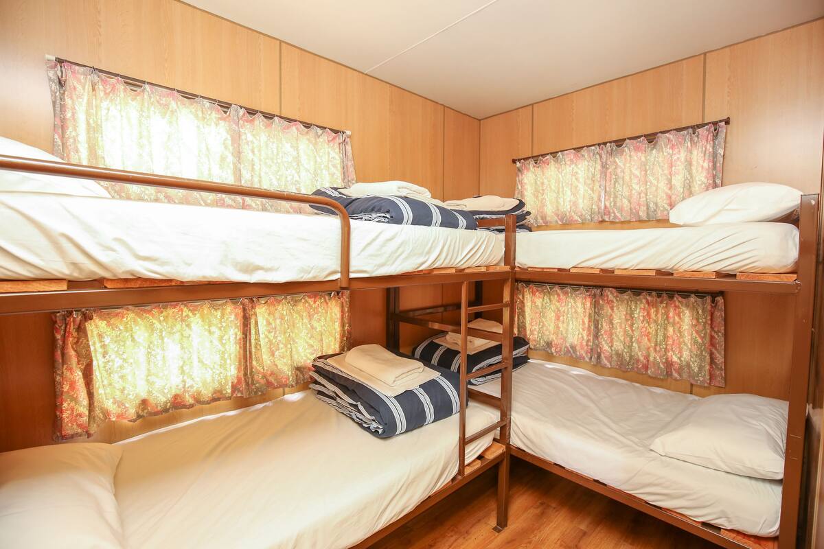 A bunk bed room with wooden walls, curtains, and a wooden floor.