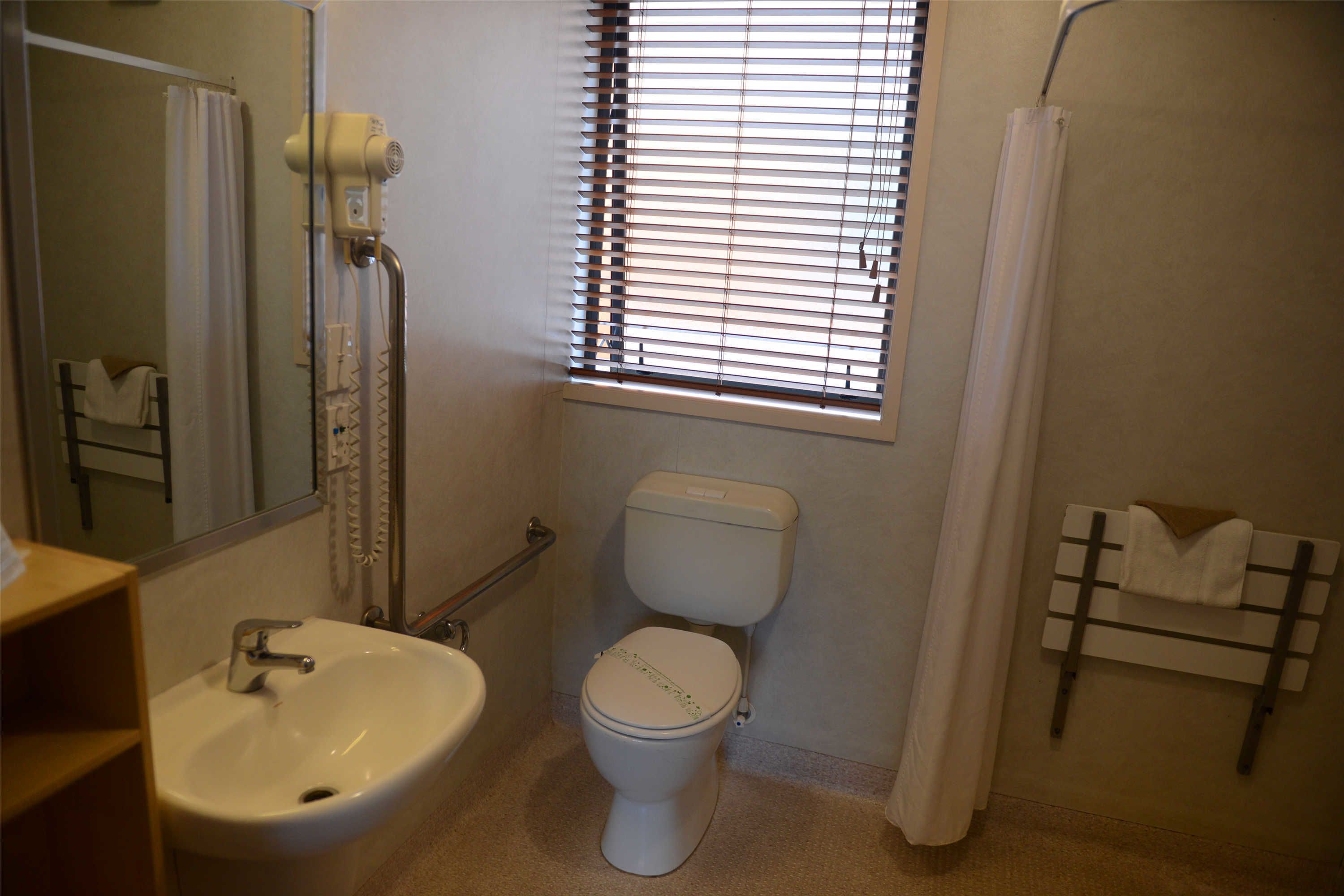 A bathroom with a white sink, toilet, and shower curtain.