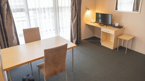A hotel room with a desk, chair, TV, and a small table. - Victoria Court Motor Lodge (Wellington)