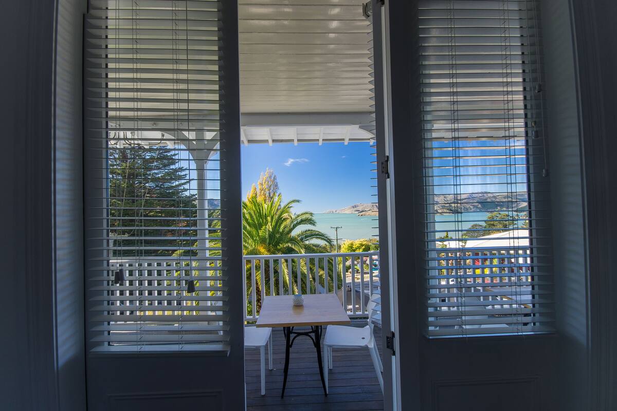 A balcony with white blinds, a small table, and two chairs.