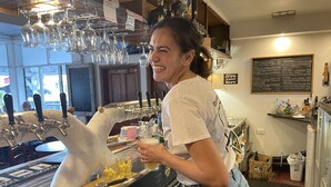 Una zona de bar con grifo de cerveza, vasos y un cartel con la carta.