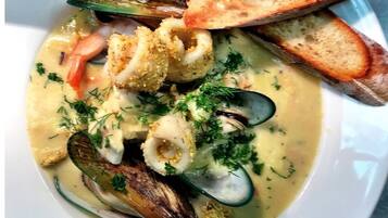 A seafood dish with mussels, clams, and bread on a white plate.