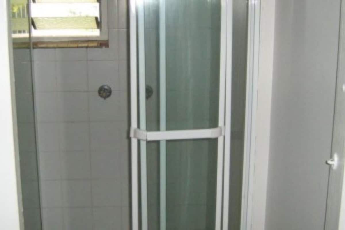 A bathroom with a shower enclosure, tiled walls, and a window above the shower.