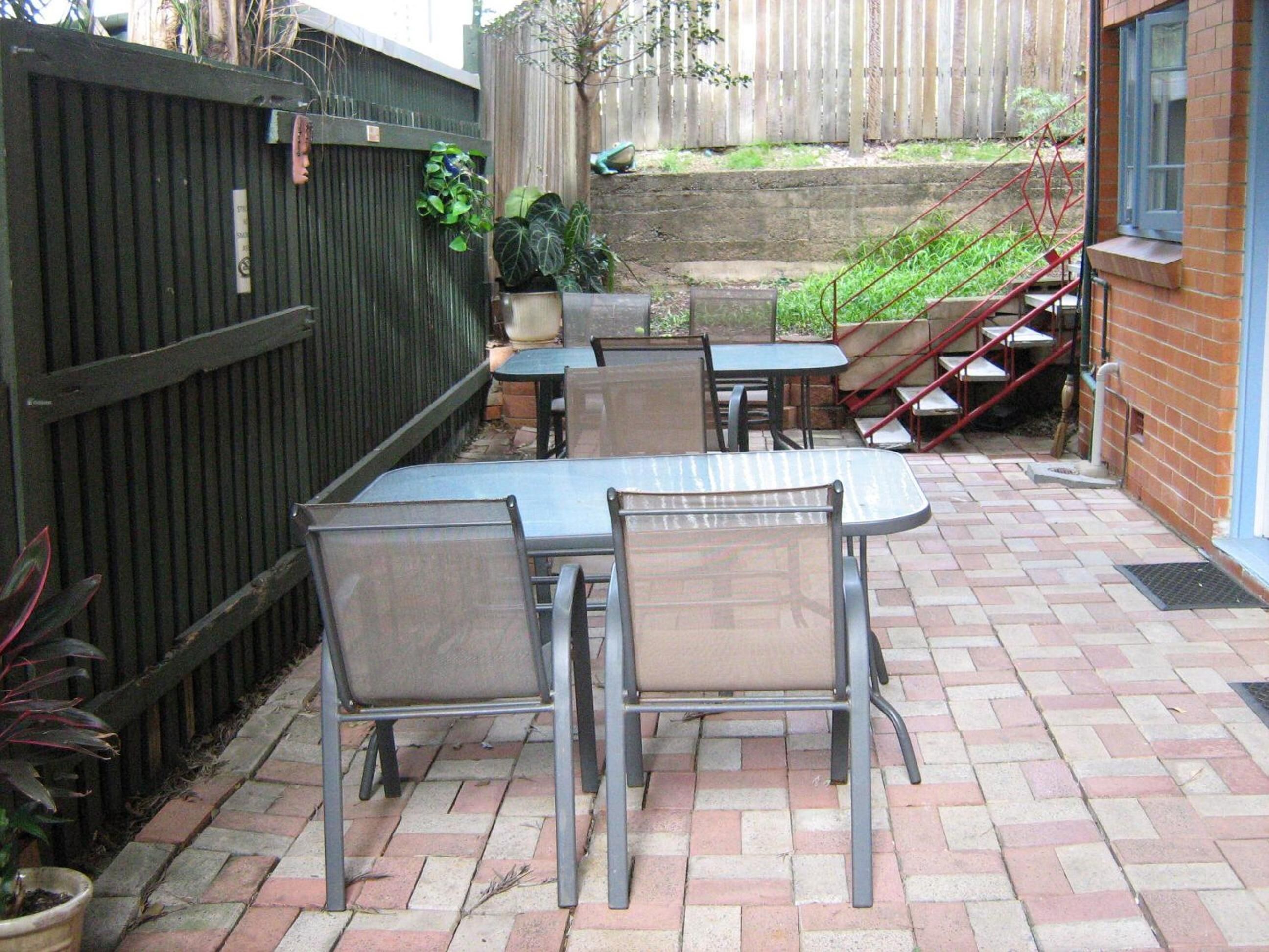 A patio with a table and chairs, a wooden fence, and a brick wall.