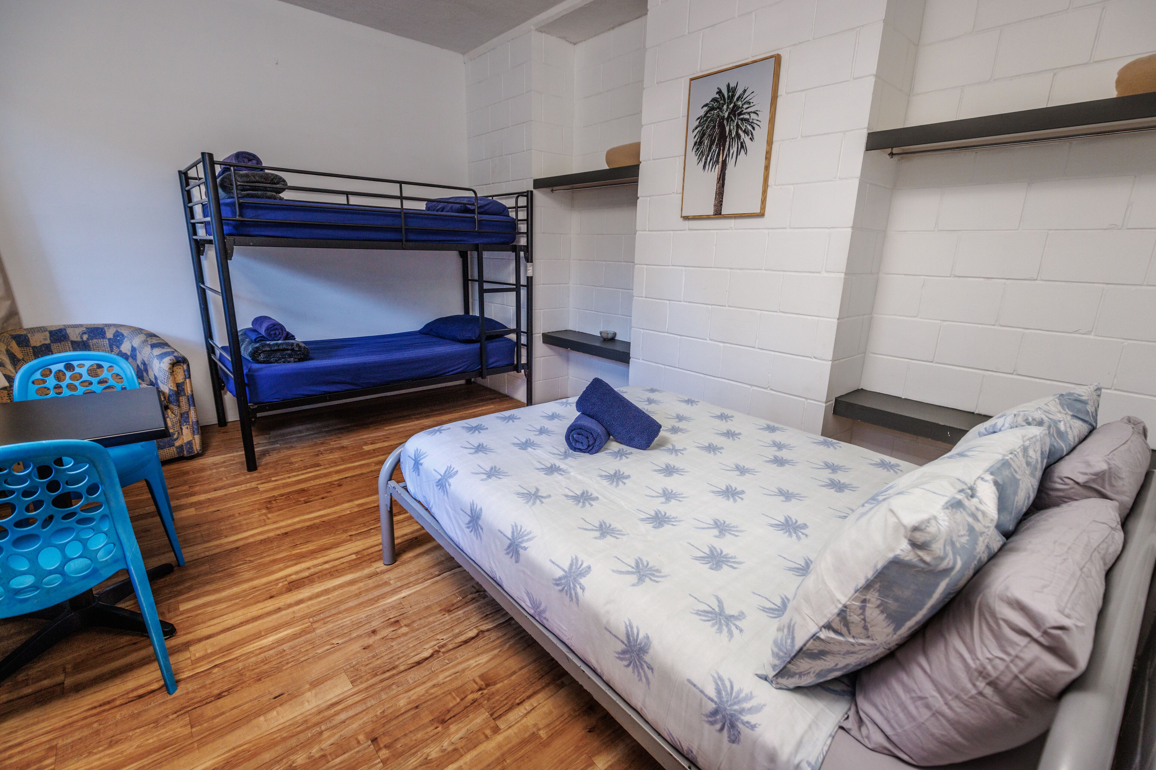 A dormitory room with bunk beds, a desk, and a chair.