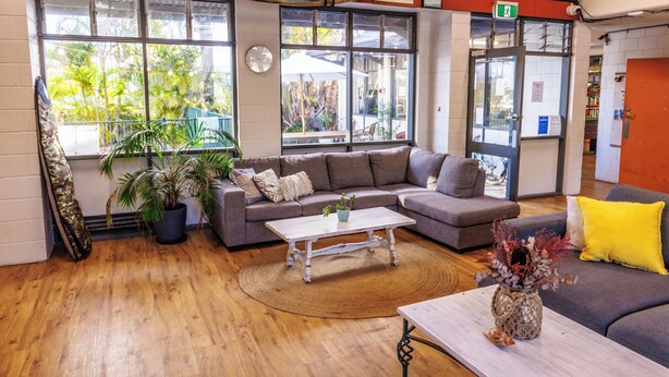 A cozy living room with a sofa, coffee table, and a plant. - YHA Coolangatta Gold Coast (Bilinga)