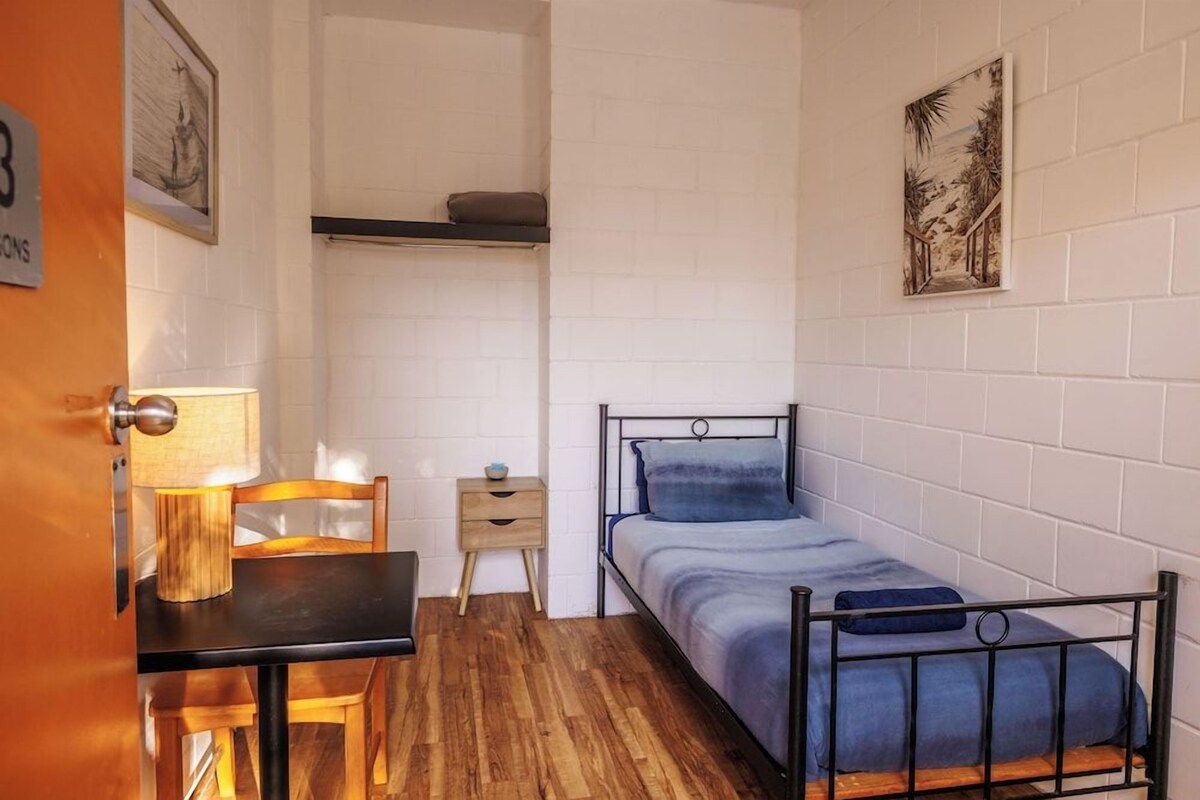Een kleine kamer met een bed, een bureau en een stoel.