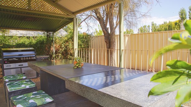 Une terrasse extérieure équipée d’un barbecue, d’un espace salon et d’une partie abritée.