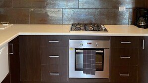 Une cuisine moderne dotée d’une hotte en acier inoxydable, d’un four encastré et d’une cuisinière à gaz.