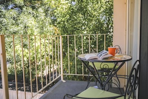 A balcony with a table and chairs, a book, and a cup. - Angaston Mews Apartments (Angaston)
