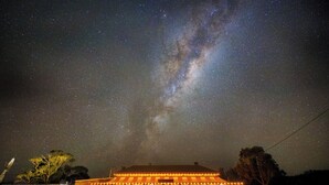 Un edificio con vista a un cielo nocturno estrellado, iluminado por luces colgantes, y una persona parada al frente.