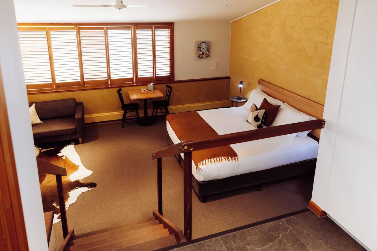 A hotel room with a bed, a sofa, a table, and a chair.