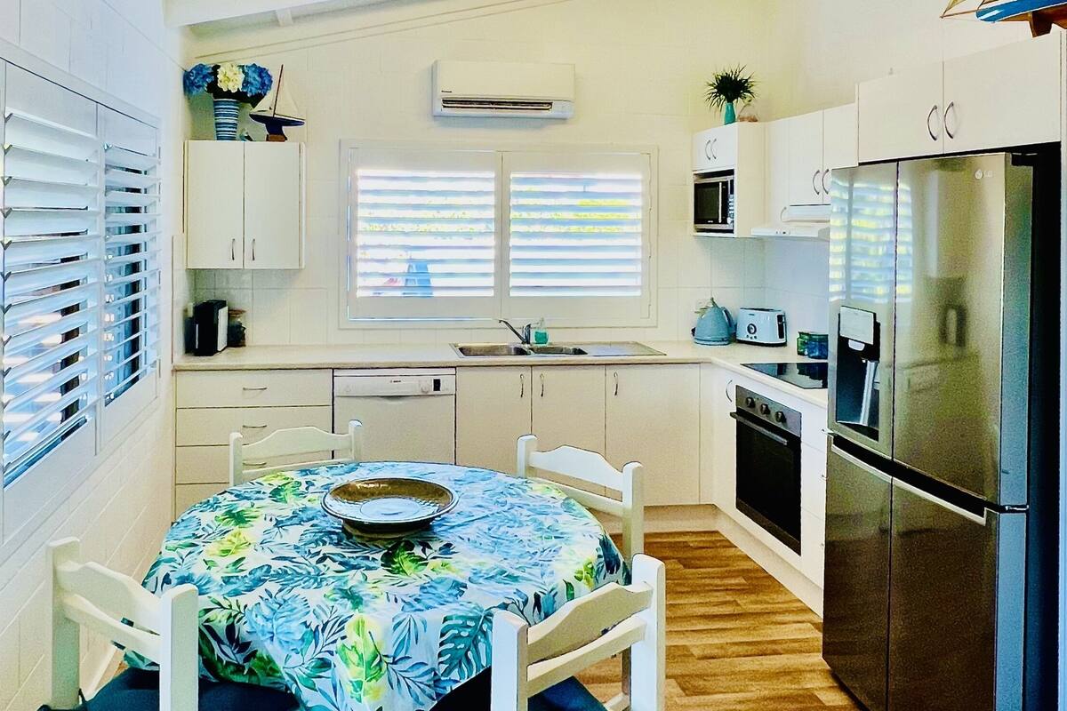 A compact kitchen with white cabinets, a stainless steel refrigerator, a microwave, and a sink.