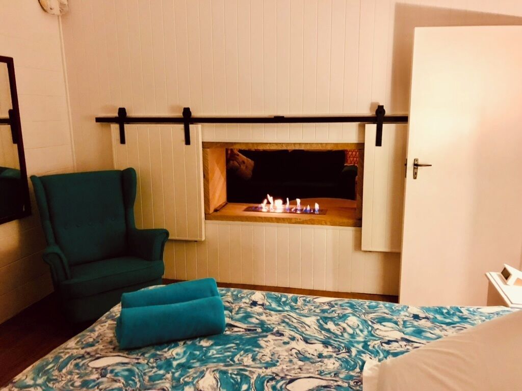 A room with a bed, a green armchair, a fireplace, and a door.