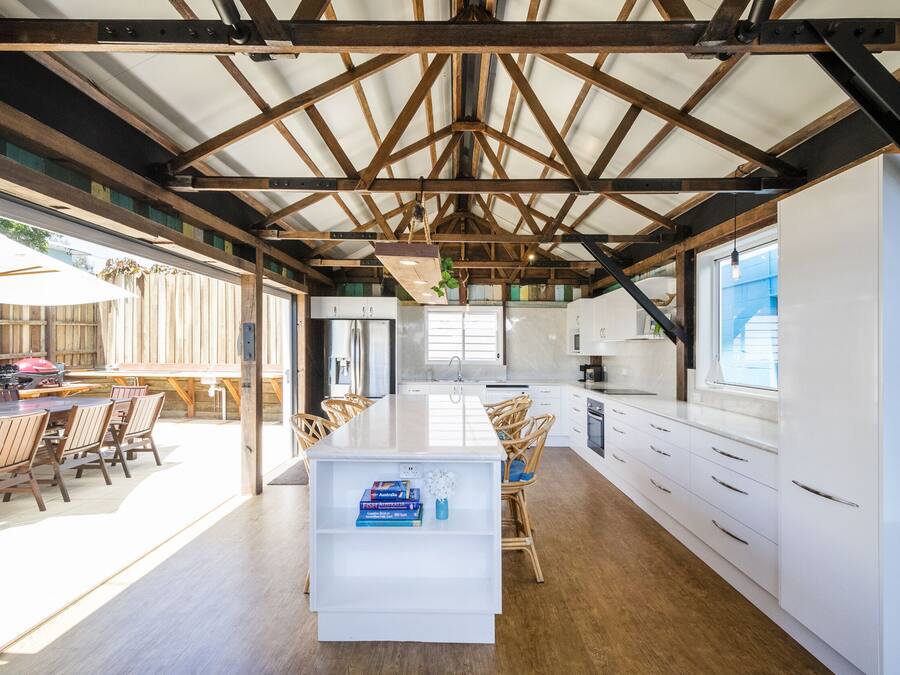A spacious kitchen with white cabinetry, a central island, and a dining area with wooden chairs and a table.