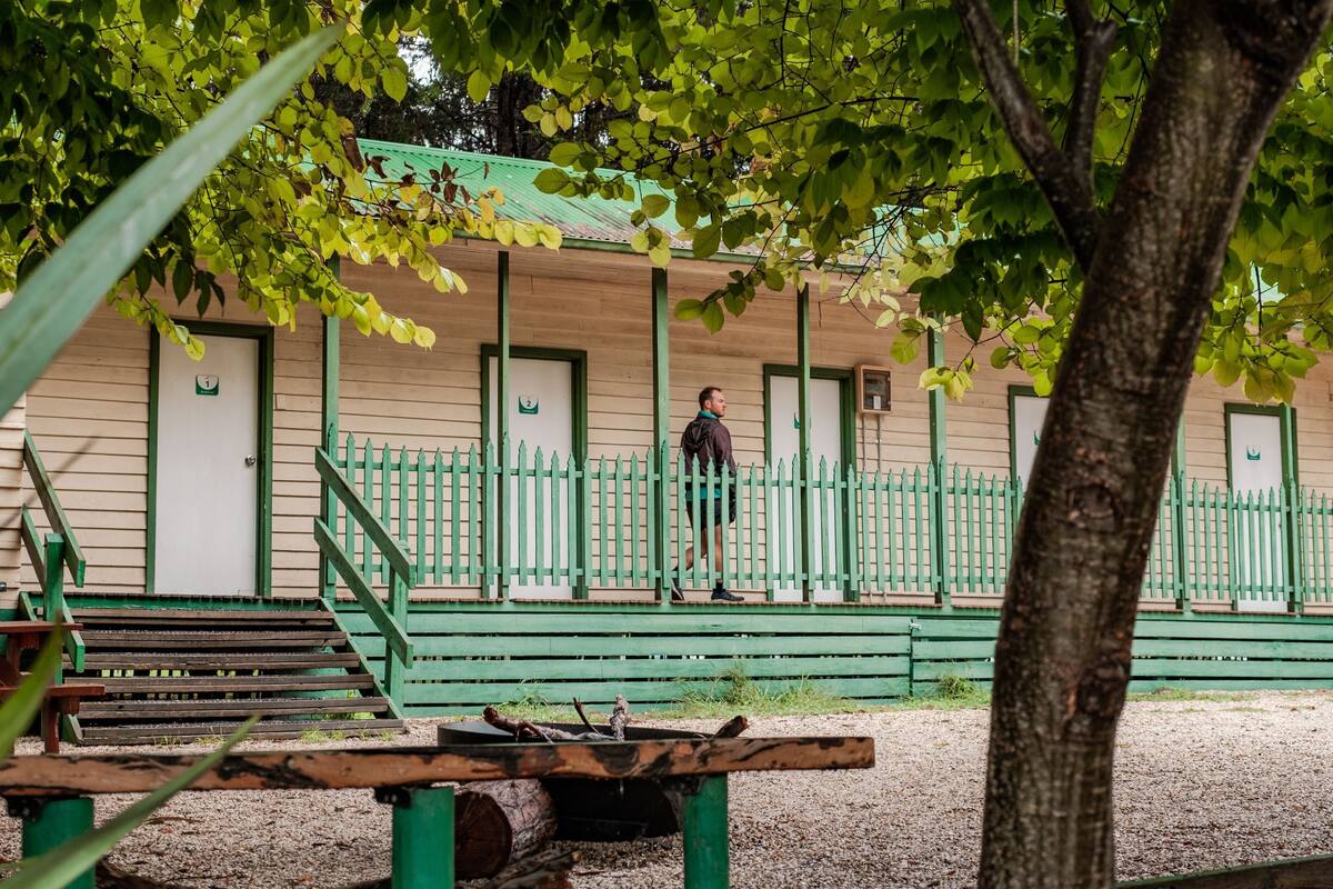 Um edifício com grade verde, uma escadaria e uma pessoa em pé nos degraus.