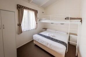 A bunk bed with a white headboard, a bedside table, and a window with curtains.