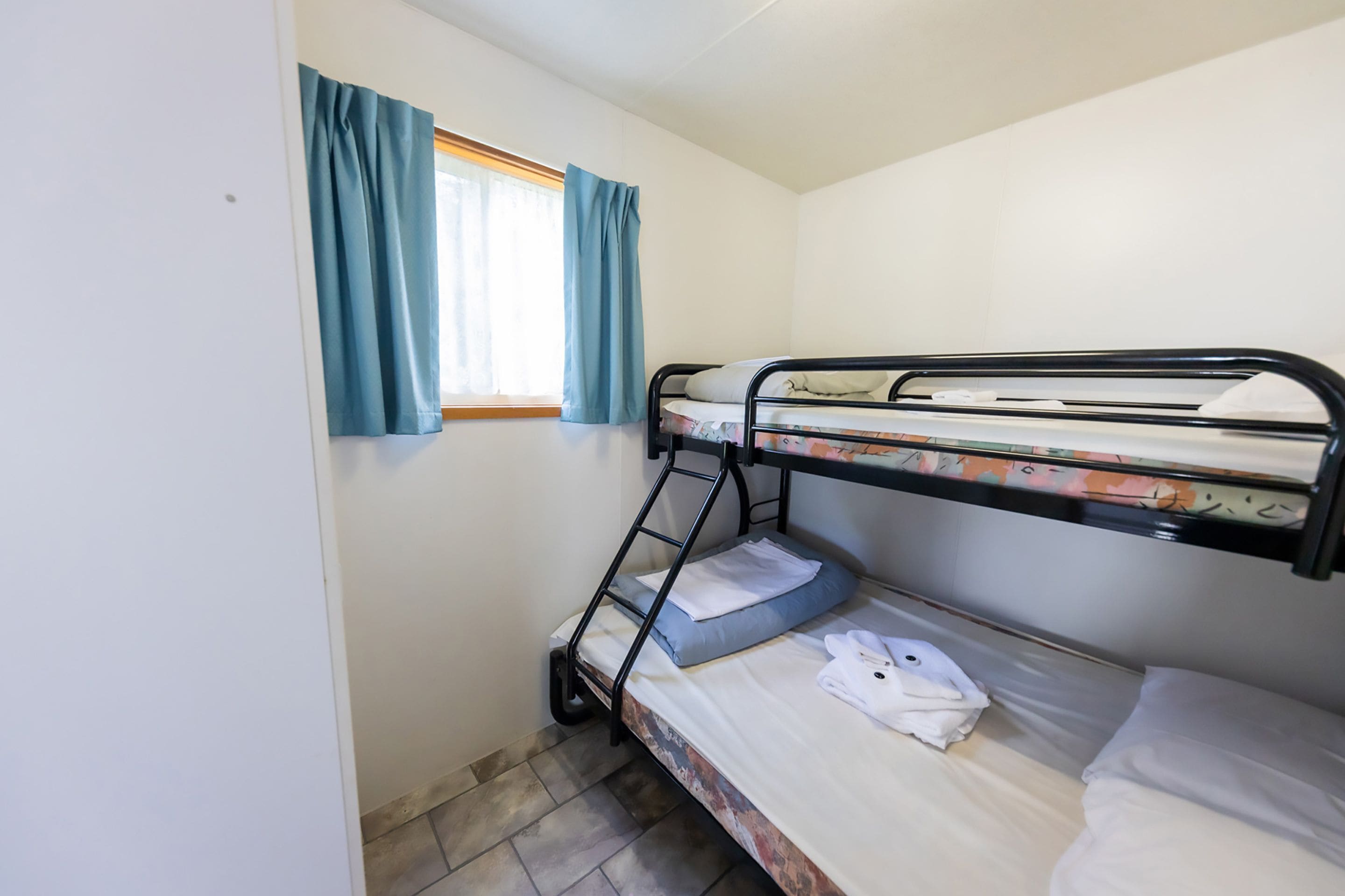 A bunk bed room with a window and curtains.
