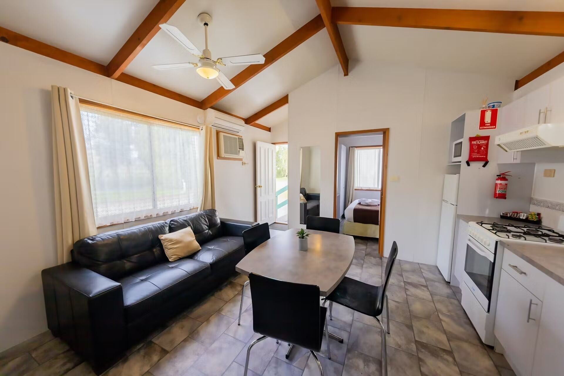 A compact living space with a sofa, dining table, chairs, a kitchenette, and a ceiling fan.