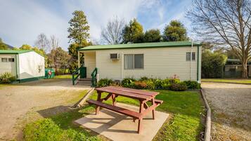 A mobile home with a picnic table in front, surrounded by a well-maintained lawn and a gravel path.