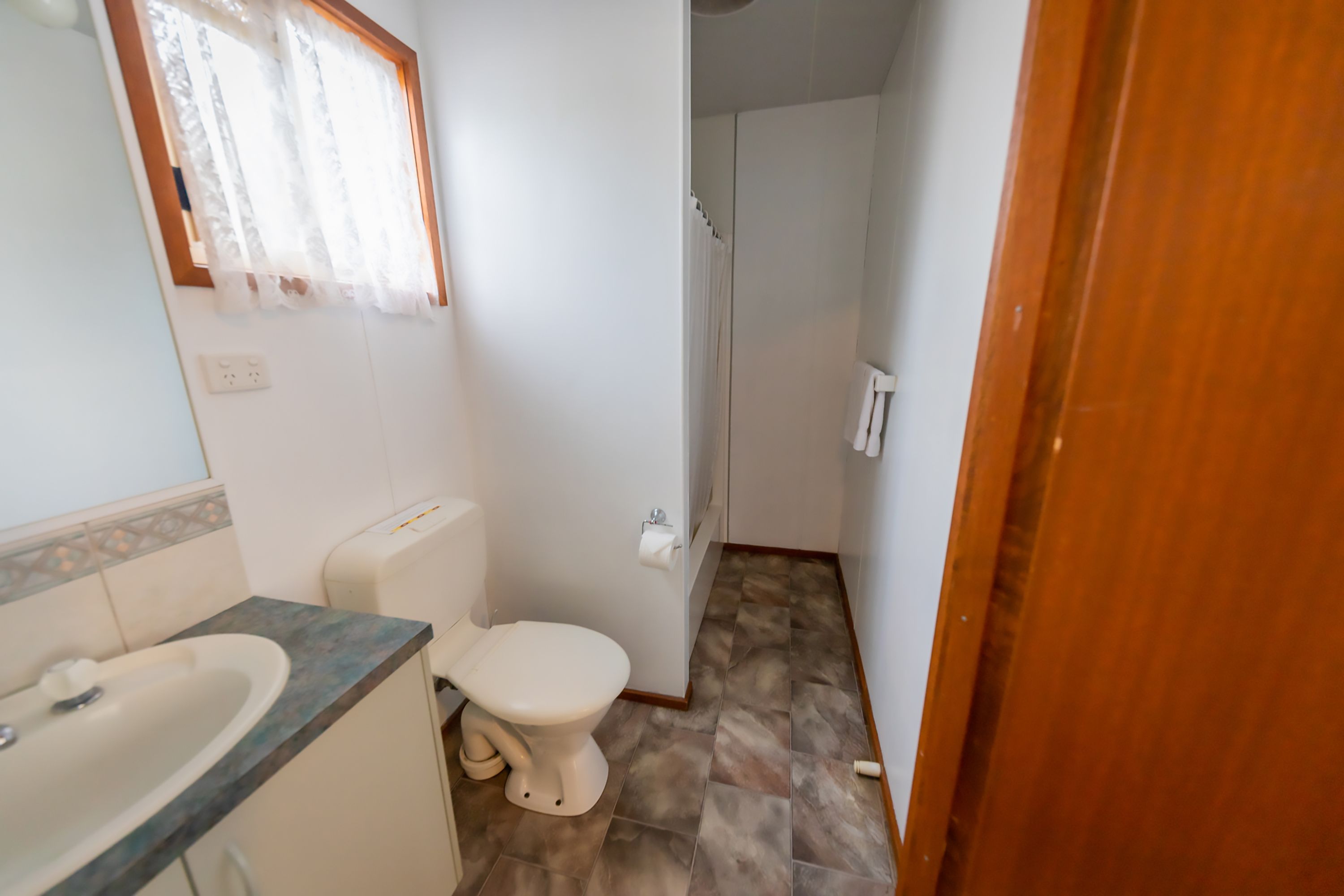 A compact bathroom with a toilet, sink, and shower.