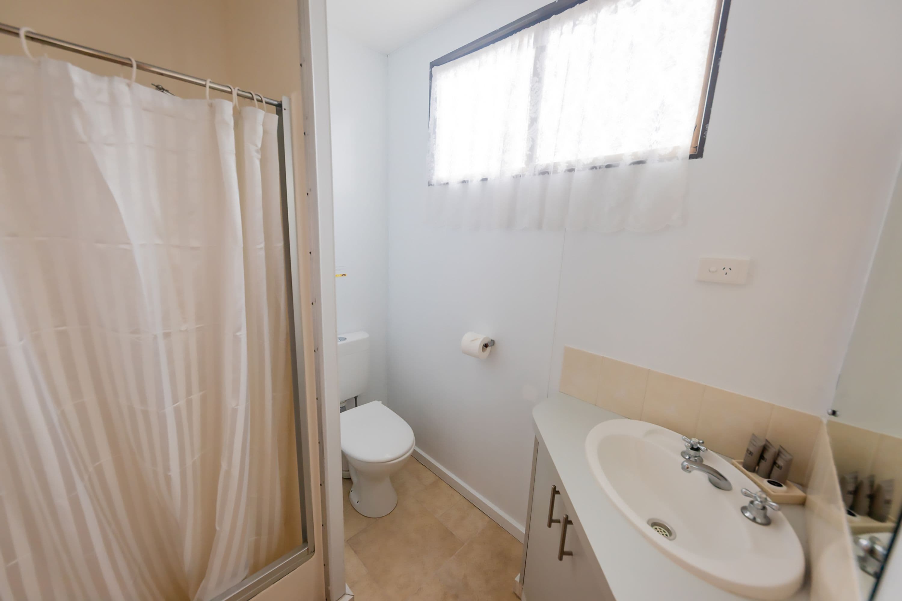A bathroom with a toilet, sink, and shower curtain.