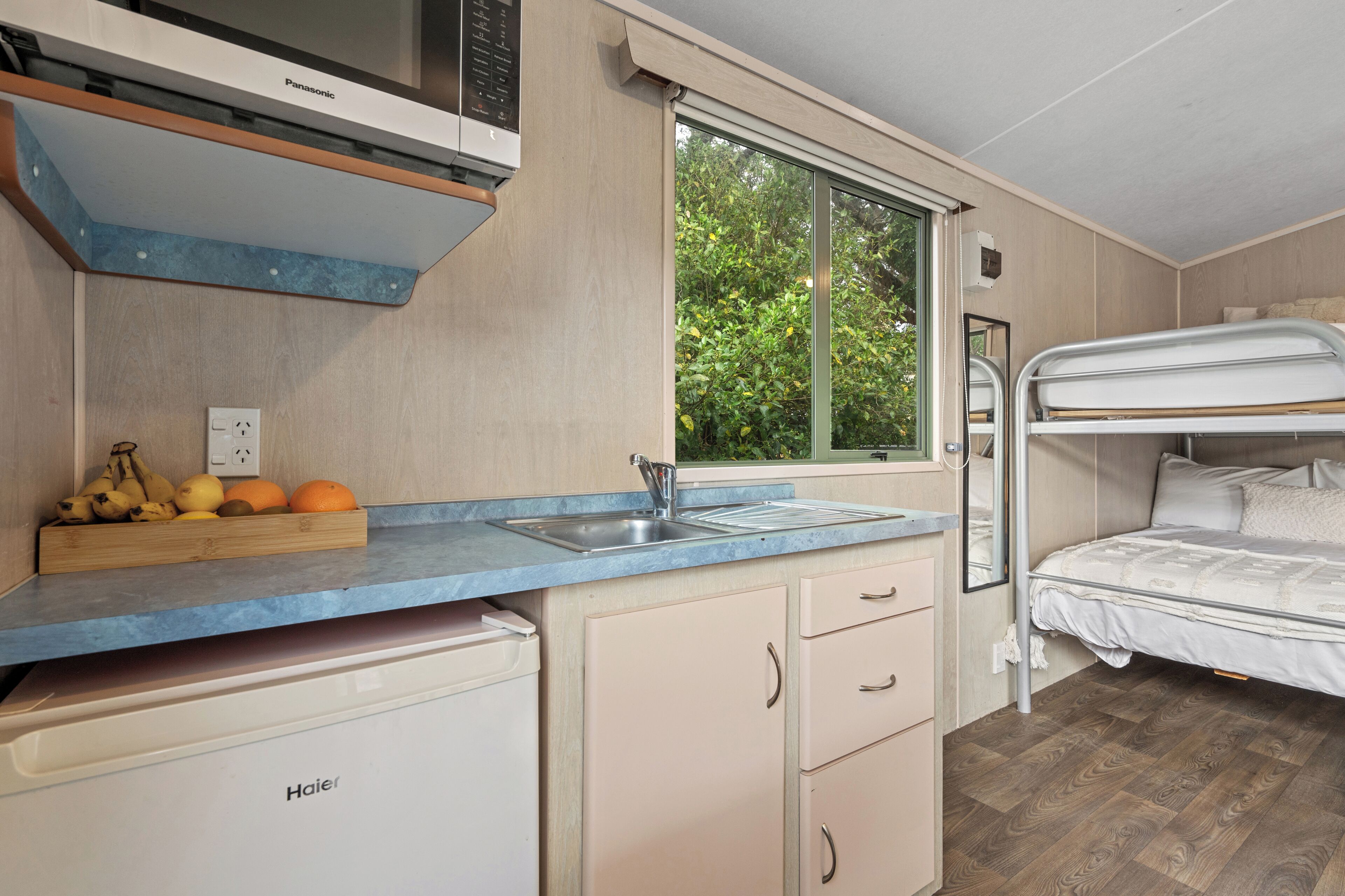 A compact kitchenette with a built-in oven, a sink, and a fruit bowl on the counter.