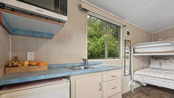 A compact kitchenette with a built-in oven, a sink, and a fruit bowl on the counter.