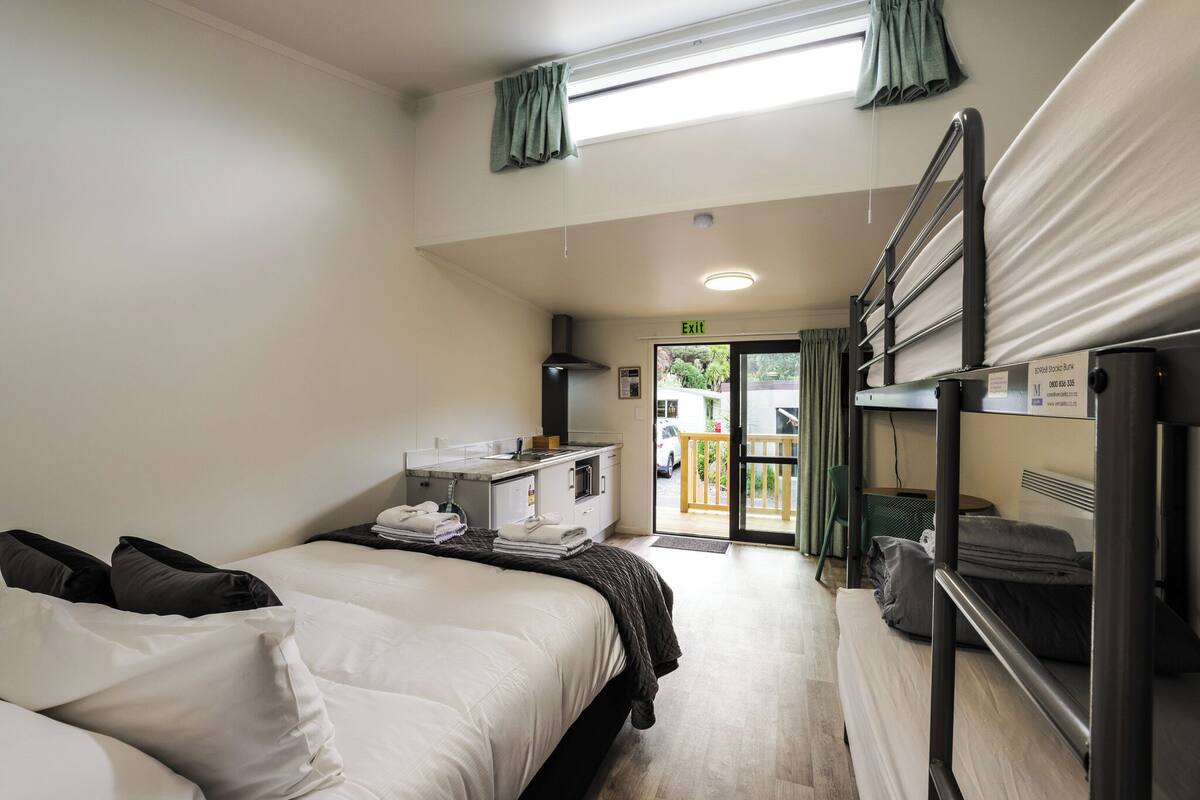 Habitación de hotel con cama, escritorio con lavamanos y balcón.