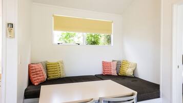 Um quarto acolhedor com um banco e mesa embutidos, uma janela com persiana amarela e um termostato na parede.