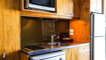 A kitchen with a microwave, stove, sink, and refrigerator.
