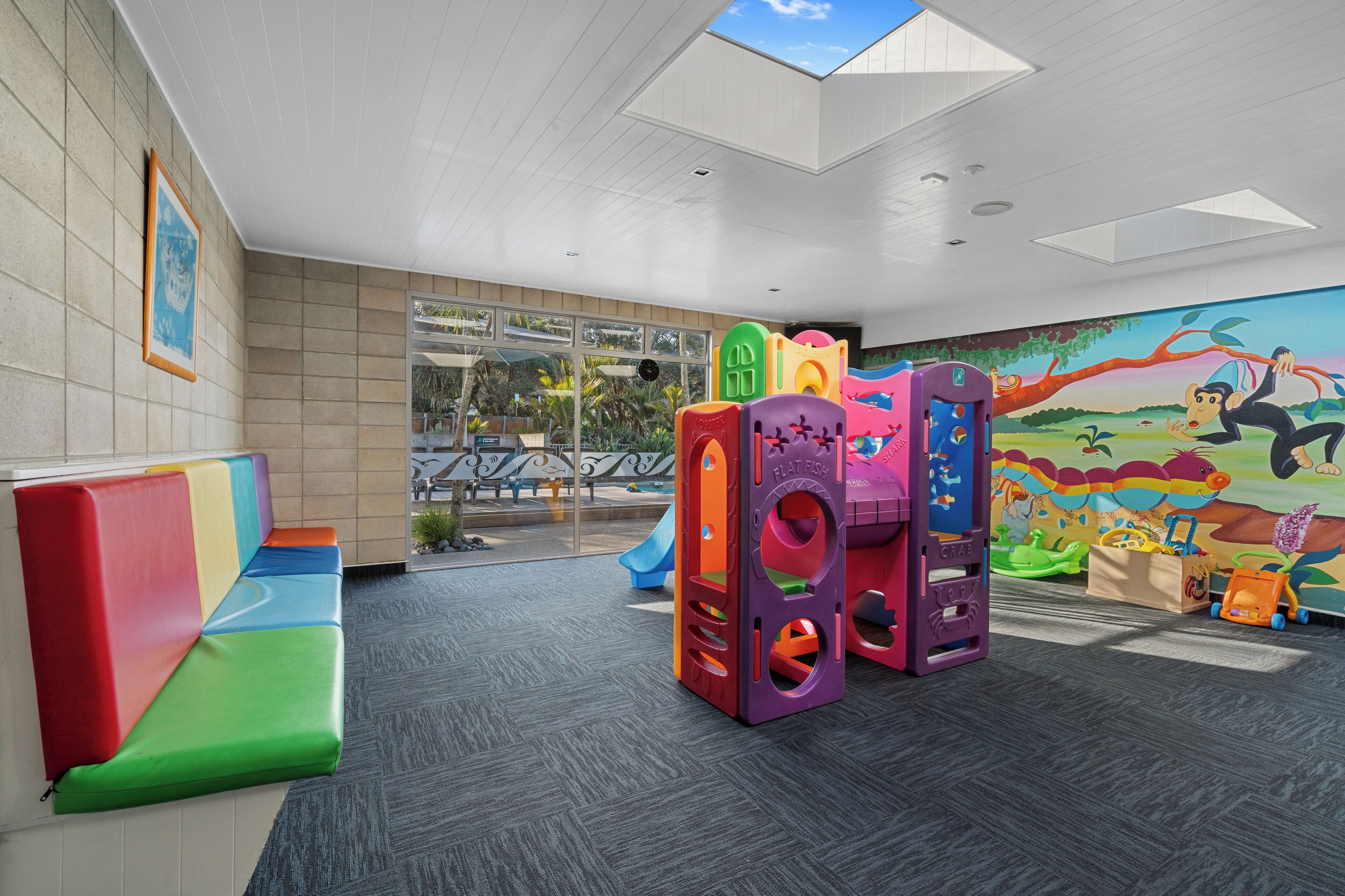 Un área de juegos infantiles con estructuras coloridas y un mural en la pared.