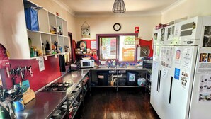 A kitchen with a stove, sink, and refrigerator, equipped with various utensils and appliances. - The Belfry Guesthouse (Bellingen)
