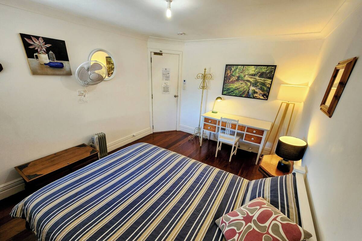 Ein Schlafzimmer mit Bett, Schreibtisch, Stuhl, Heizkörper und Lampe.