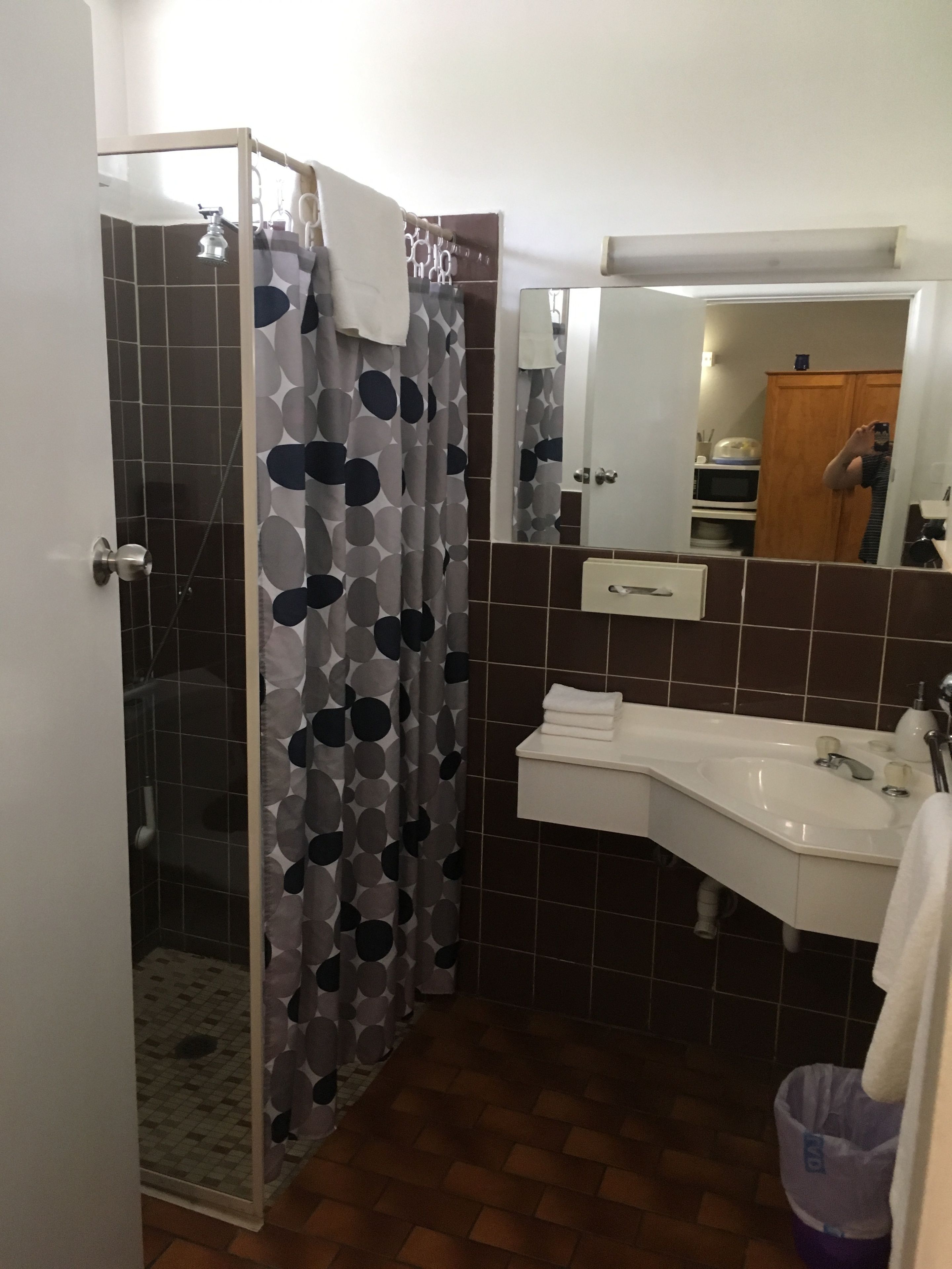 A bathroom with a shower, a sink, and a mirror.