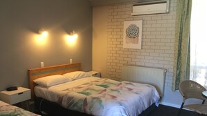 Ein Hotelzimmer mit Bett, Nachttisch, Lampe und einem Sessel.